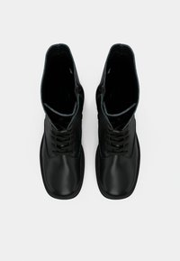 Ζευγάρι μαύρων δερμάτινων μποτών με κορδόνια και τετράγωνες μύτες, προσανατολισμένο από πάνω σε λευκό φόντο.