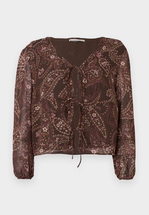 Brūns rakstains blūze ar garām elastīgām piedurknēm, V-veida kakla izgriezumu un priekšējo sasienamo detaļu. Satur ziedu un paisley dizainus bālās krāsās.