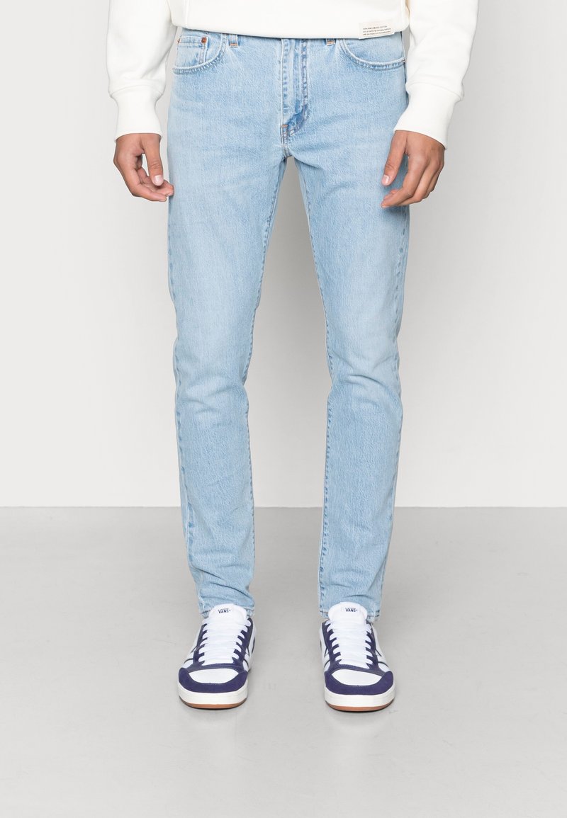 Ljust blå denimjeans med slim fit, som har framfickor, en klassisk femfickedesign och subtila blekningar. Matchas med vita och marinblå sneakers.