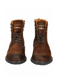 Botas de tobillo de cuero marrón con un acabado texturizado, que cuentan con un cuello de piel sintética, ojales metálicos y suelas de goma negra resistentes.