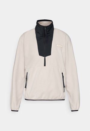 Pull à col zippé noir en polaire beige clair. Caractéristiques : panneau vertical noir et poches latérales zippées. Texture douce.