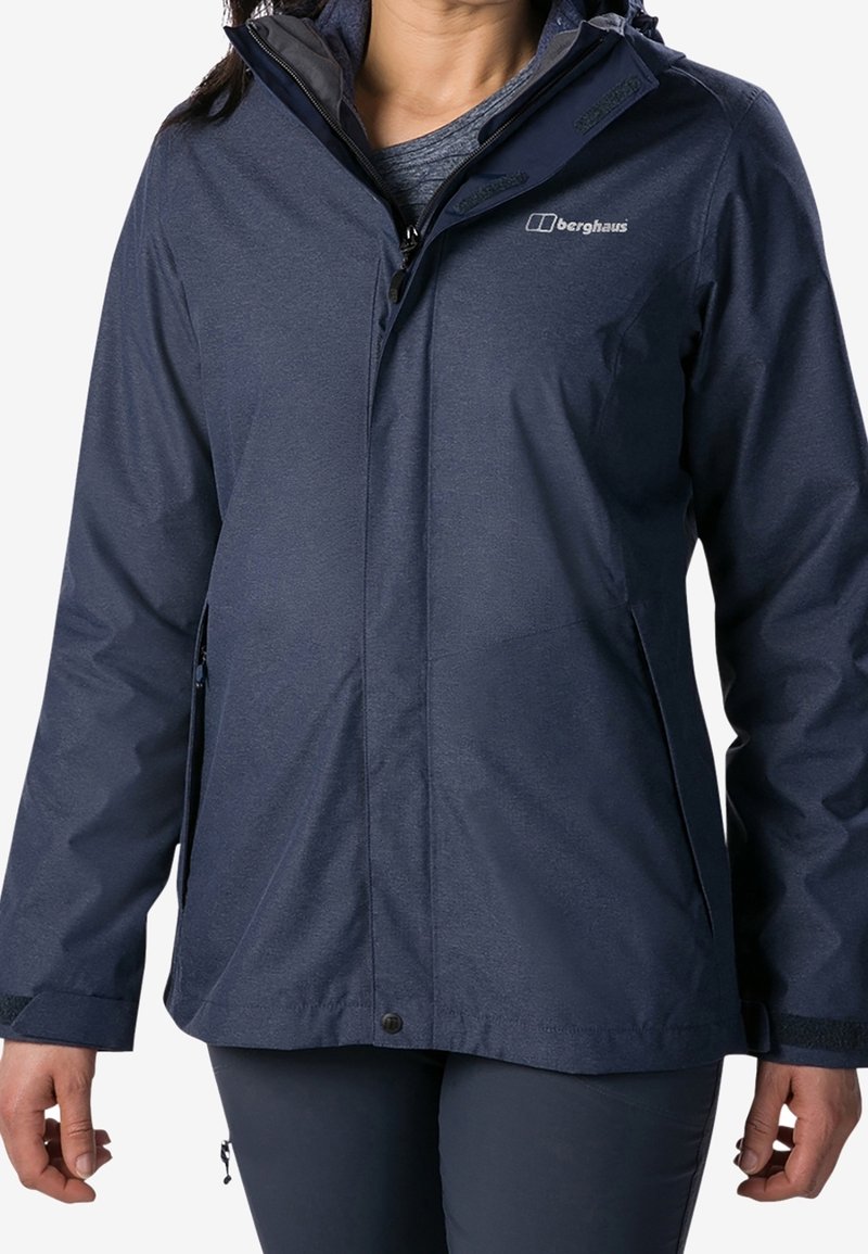Marinblå vattentät jacka från Berghaus med dragkedja fram, justerbara manschetter och en hög krage med huva. Mjuk, texturerad tyg.