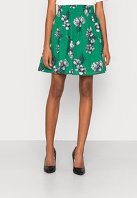 Groene bloemenrok gemaakt van lichtgewicht stof, met een geplooid ontwerp, tropische bloem- en bladdessins en een elastische tailleband.