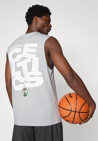 Pilkas be rankovių krepšinio marškinėliai su dideliais baltais užrašais "BOSTON CELTICS" ant nugaros, su logotipu apačioje, derinami su oranžiniu krepšiniu.