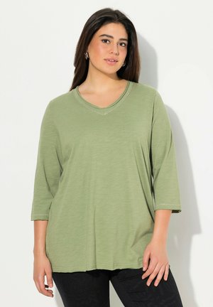 Grünes, leichtes Longsleeve-Oberteil mit V-Ausschnitt, das über subtile Nähte verfügt. Der lockere Schnitt fällt bequem über den Körper.