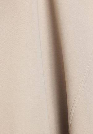 Beige stof met een gladde textuur, met subtiele rek. Het oppervlak straalt een uniforme kleur uit met fijne stiksel langs de randen.