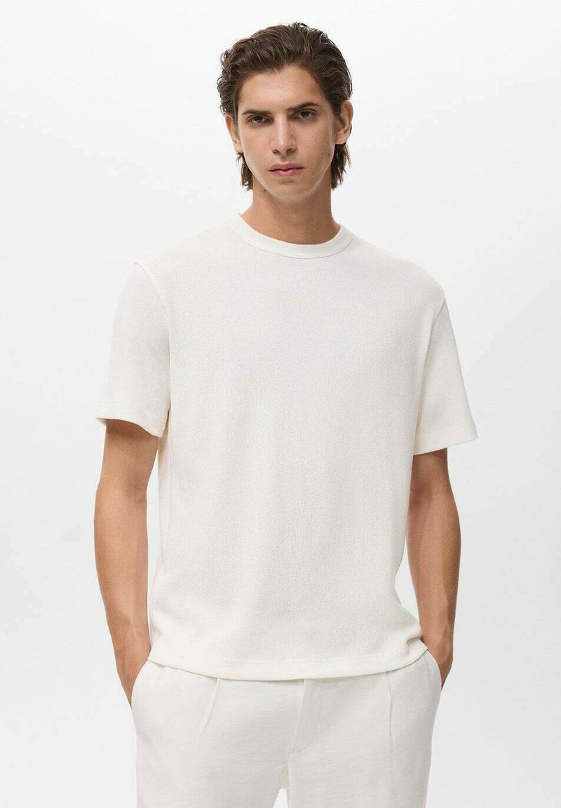 Tricou alb, cu mânecă scurtă, realizat dintr-un material texturat, cu decolteu rotund. Purtați cu pantaloni asortați de culoare deschisă. Design simplu, minimalist.