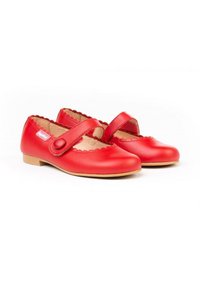Zapatos Mary Jane de cuero rojo con bordes en forma de escallo, una sola correa y puntera redonda. Suela plana para comodidad y estabilidad.