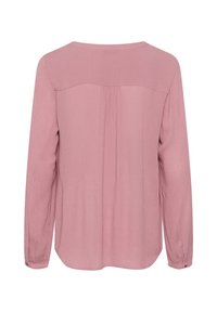 Blouse rose pâle à manches longues, texture lisse, encolure arrondie et plis dans le dos. Poignets boutonnés inclus.