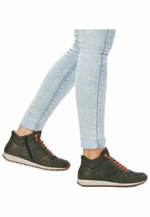 Tummanvihreät korkeavartiset kengät oransseilla nauhoilla, sivuvetoketjulla ja teksturoiduilla paneeleilla. Pohja on vaalea, kuvioitu kulutuspinnalla. Käytetty vaaleiden farkkujen kanssa.