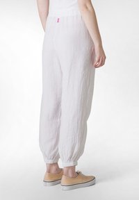 Lette, hvide linnedbukser med en samlet talje og elastiske manchetter. Sammen med beige sneakers og en simpel hvid top.