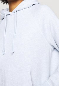 Felpa leggera azzurra, realizzata in tessuto morbido, con tasca a marsupio, cordini sul cappuccio e maniche raglan per un fit rilassato.