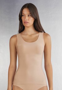 Nude tanktop met een ronde hals, mouwloos ontwerp, zachte textuur en aansluitende silhoutte, ideaal voor het dragen in lagen of als aparte outfit.