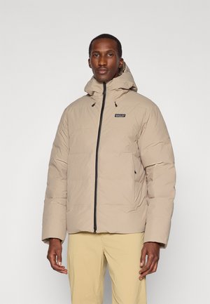 Beige puffer jacket with a zip closure and adjustable hood. Features black accents and side pockets, made from a lightweight, insulated material.