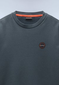 Donkergrijze sweatshirt met een ronde hals, voorzien van een oranje bies aan de binnenkant van de kraag en een ronde logo op de borst. Glad stoftextuur.