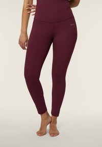 Leggings bordeaux in tessuto elastico, con vita alta, vestibilità aderente e lunghezza alla caviglia. Nessun motivo o hardware visibile.