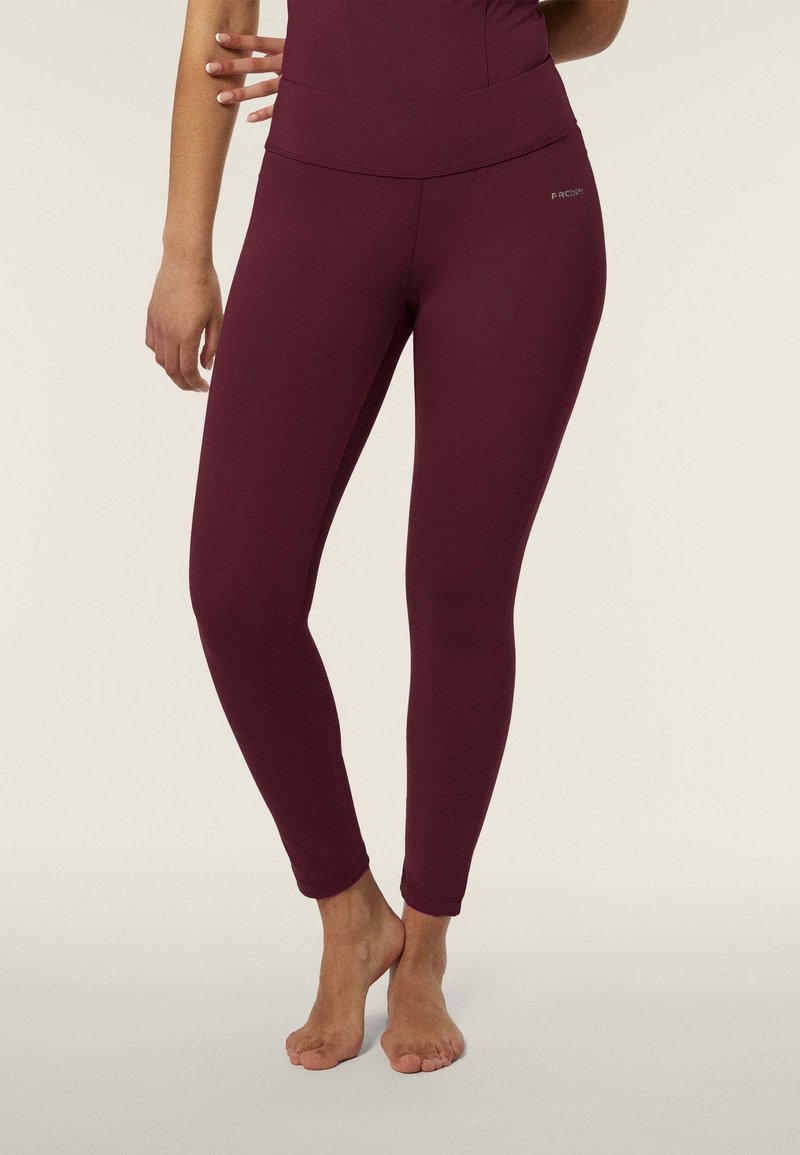 Leggings bordeaux in tessuto elastico, con vita alta, vestibilità aderente e lunghezza alla caviglia. Nessun motivo o hardware visibile.