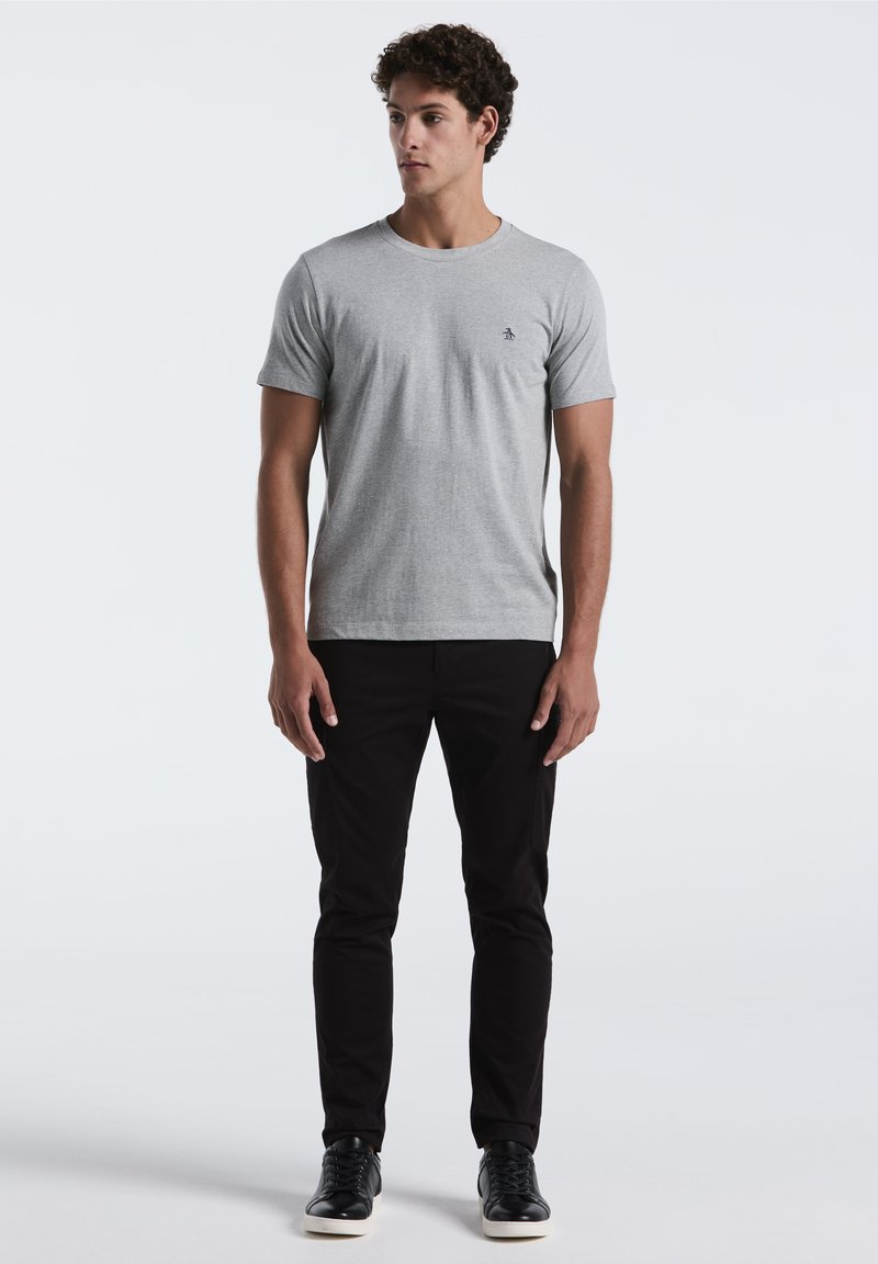 Grijze katoenen t-shirt met een ronde hals en korte mouwen, gecombineerd met zwarte slim-fit broek en zwarte sneakers met witte zolen.