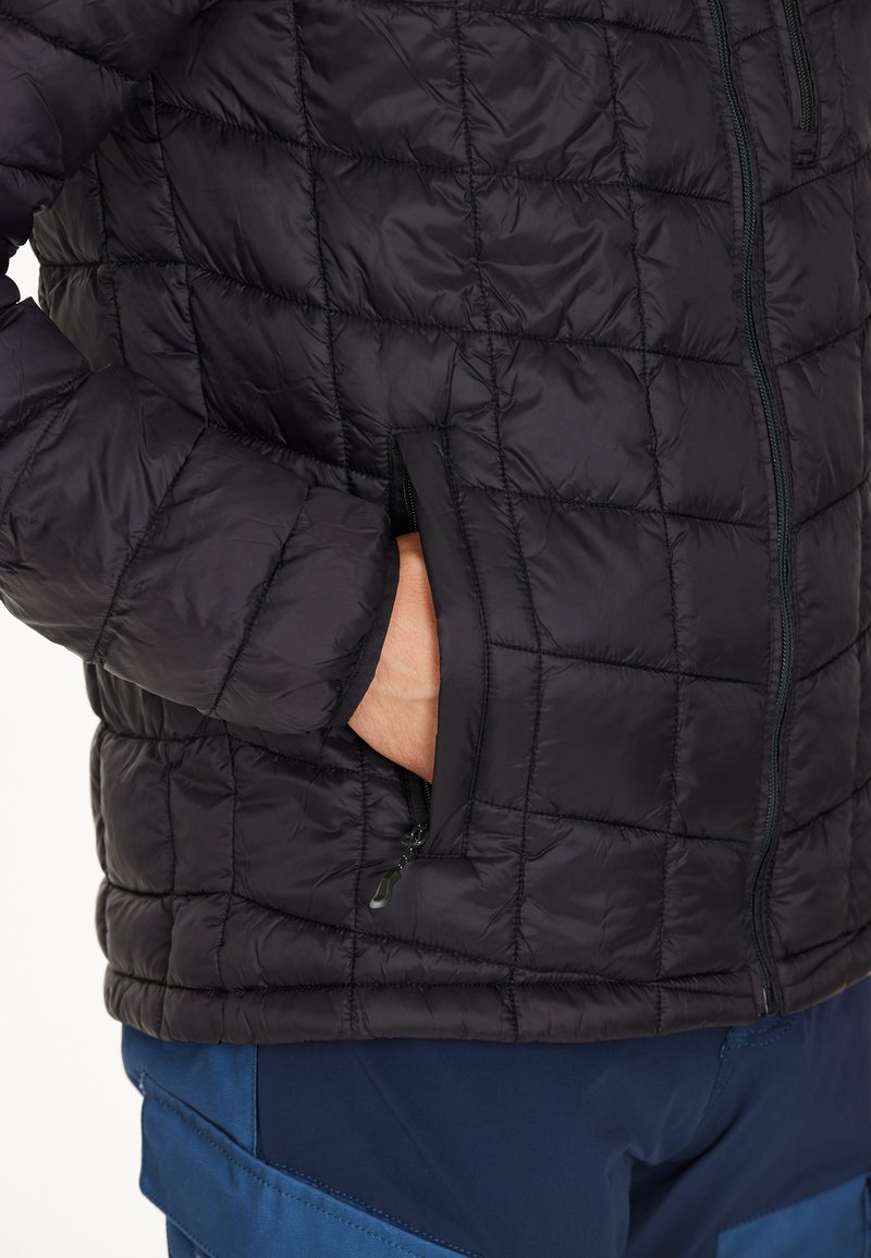 Zwarte gewatteerde pufferjas met een rits aan de voorkant, zijzakken en een gestructureerde stof. Heeft een slim fit ontwerp en lichte isolatie.