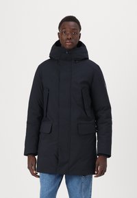 Parka imbottita blu navy con colletto alto, cappuccio regolabile, due tasche frontali e chiusura a zip. Presenta una superficie liscia e opaca.