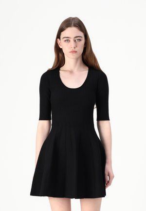 Black ribbed dress with short sleeves, scoop neckline, fitted bodice, and flared skirt featuring vertical paneling. Soft texture.