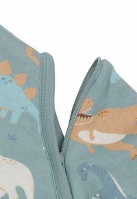 Tissu bleu clair avec des motifs de dinosaures, doté d'une fermeture éclair et de coutures plates pour une finition lisse. Texture douce et design ludique.
