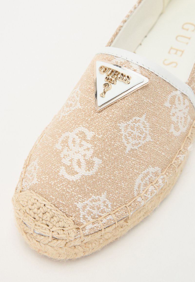 Espadrille-Schuh aus beigem Stoff mit weißen Logos, ausgestattet mit einem dreieckigen Metall-Logo-Akzent und einer gewebten Jutesohle mit genähtem Rand.