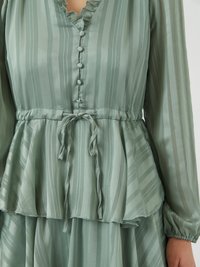 Φόρεμα peplum σε ανοιχτό πράσινο, με κάθετες ρίγες, ρυζωμένο λαιμόκοψη, λεπτομέρειες με κουμπιά στη μπροστινή πλευρά και ζώνη που δένει στη μέση. Απαλή, μεταξένια υφή.