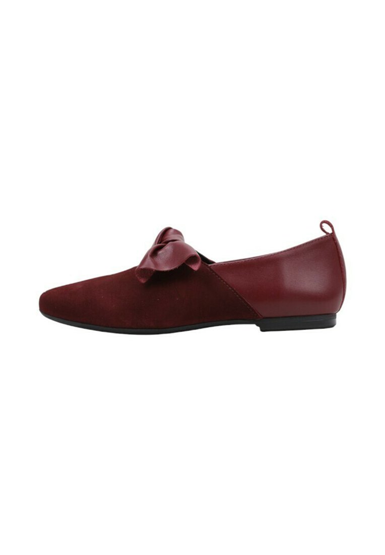 Zapato plano burdeos con un acabado de ante suave, puntera afilada y un lazo decorativo en la parte superior. Diseño simple con un tacón bajo y redondeado.