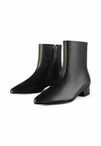 Zwarte enkellaarzen van glad leder met een gespte neus en een lage blokhak. Voorzien van een rits aan de zijkant en een slank design.
