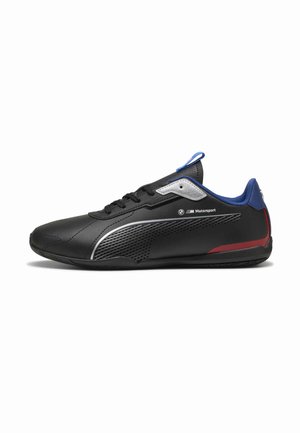 Chaussure Puma Motorsport noire profil basse avec col bleu, détail rouge au talon, accents argentés et bande latérale texturée.