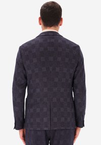 Blazer a quadri scuro con una forma strutturata, realizzato in tessuto testurizzato con un motivo a griglia nelle tonalità di blu navy e viola, con uno spacco sul retro.