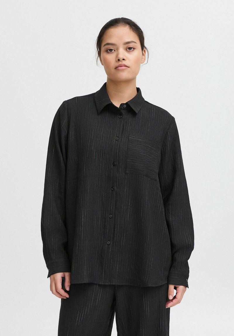 Zwarte langearmige shirt met een kraag, voorzien van een textuur met dunne verticale strepen en een linkerkant borstzak.