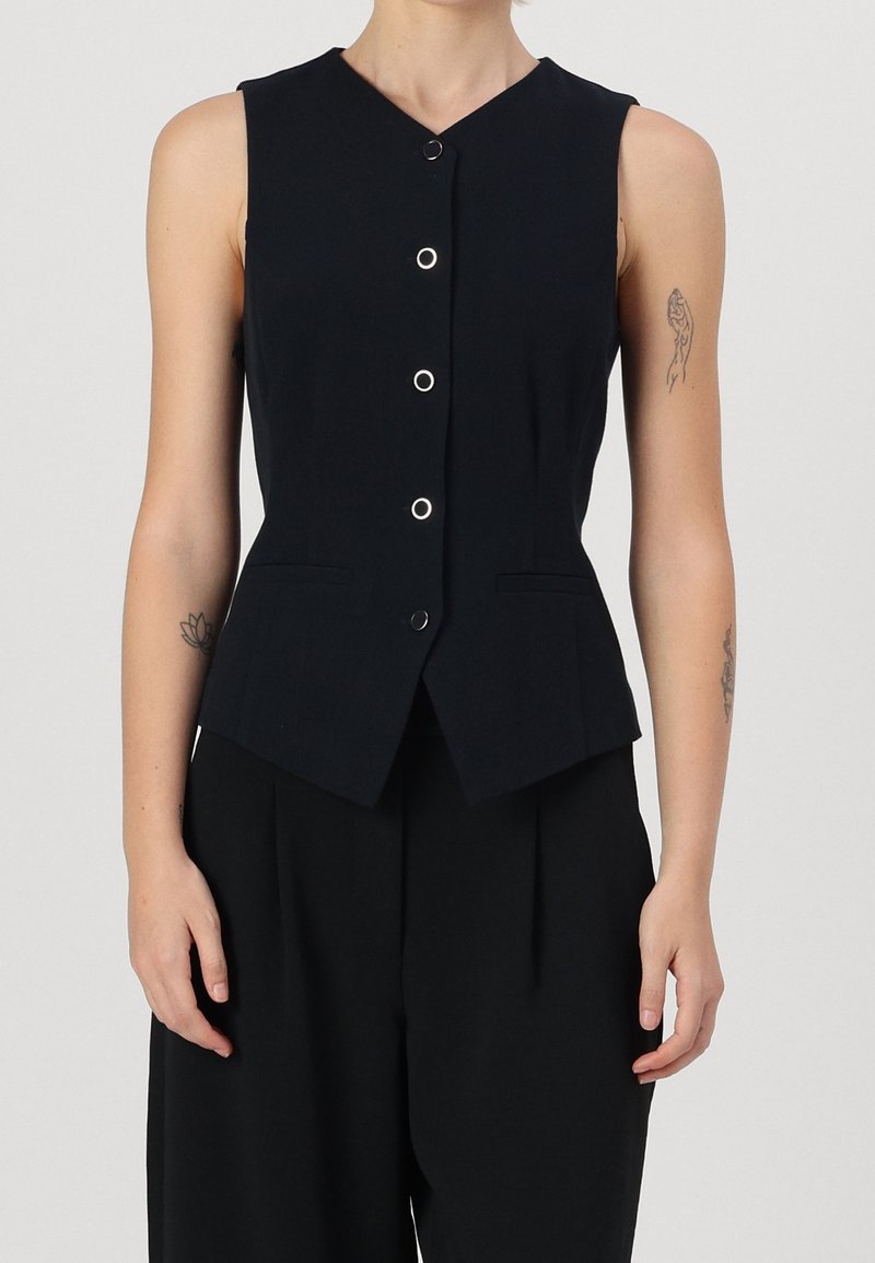 Navy sleeveless vest with a V-neck, five metallic buttons, two front pockets, and a fitted silhouette tapering at the waist.