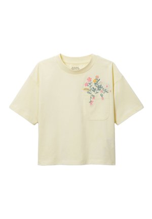T-shirt jaune clair à manches courtes avec col rond et poche avant ornée de fleurs brodées roses et jaunes avec des tiges vertes.
