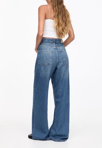 Breda blå jeans i denim med hög midja, två bakfickor och en ren finish med minimal slitage.