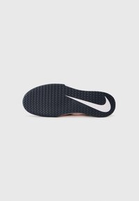 Crna potplat od cipele s teksturiranim uzorkom, s bijelim Nike swoosh logom sa strane. Glatke ivice i malo uzdignuta peta.