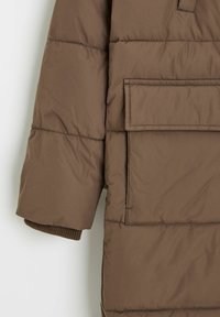 Brązowa kurtka puchowa z pikowanym wzorem, dużą przednią kieszenią i ściągaczami na rękawach. Gładka tekstura i minimalistyczny wygląd.