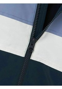 Färgblockerad jacka med paneler i marinblått, ljusblått och vitt. Centrerad dragkedja med svarta detaljer och strukturerad tygytan.