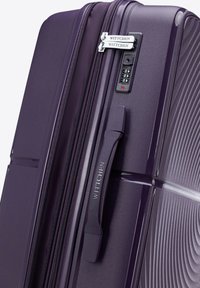 Valigia viola con texture rigata, doppi manici e serratura a combinazione. Presenta un marchio e un design della superficie liscia.