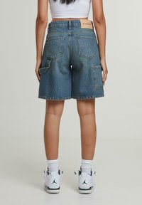 Gaišu zilu denim bermaudu šortu komplekts ar četrām kabatām, nedaudz brīvāku piegriezumu un izšūtu logo etiķeti aizmugurējā jostasvietā.