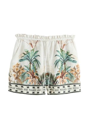 Fehér vászonnadrág trópusi pálma- és virágmintával, elasztikus derékpánttal és fekete feliratos szalaggal, amely hawaii helyneveket tartalmaz.