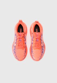 Baskets de sport orange avec une tige en mesh, un motif texturé, des lacets et un col rembourré. La semelle est légèrement surélevée avec une adhérence en caoutchouc.