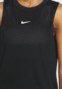 Top deportivo sin mangas de color negro con tejido texturizado, escote redondo y un pequeño logo blanco de Nike en el pecho.