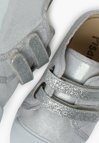 Srebrne buty z teksturowanym, metalicznym wykończeniem, z dwoma błyszczącymi rzepami i białą gumową podeszwą dla lepszej przyczepności.