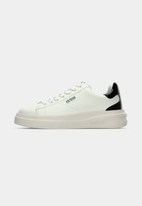 Weiße Ledersneaker mit einem schwarzen strukturierten Fersenelement, dicker off-white Sohle und silbernem "GUESS"-Logo an der Seite.
