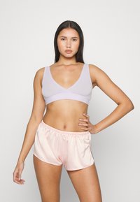 Bralette lavanda com um decote em V profundo e alças largas, combinado com calções de satin rosa claro com um cós elástico e um acabamento suave.