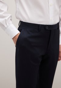 Pantalones a rayas marinos hechos de tela con un ligero brillo, con cinturilla abotonada y bolsillos laterales.