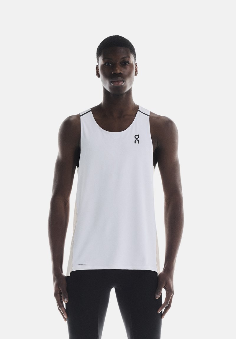 Hvid atletisk tanktop med sorte accenter og logo, lavet af letvægts, åndbart stof og en løs pasform, ideel til træning.