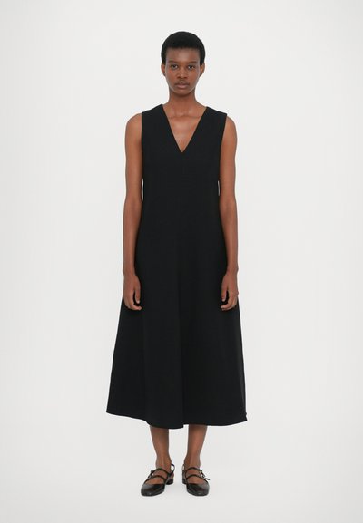 Robe noire sans manches avec un col en V, à silhouette évasée, longueur genou. Texture de tissu lisse, design minimal, sans motifs ni accents visibles.
